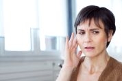 Frau mit irritiertem Blick hält sich ihr rechtes Ohr Frau mit irritiertem Blick hält sich ihr rechtes Ohr